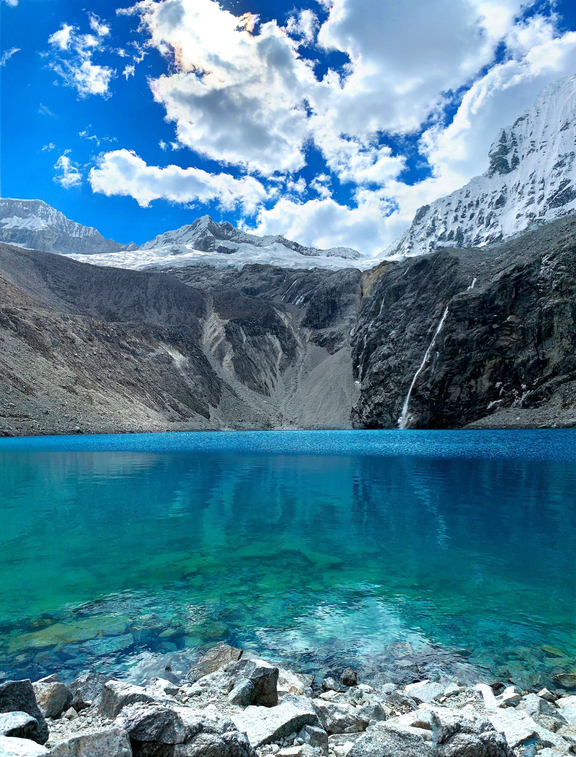 Lake Paron with mountains in the background and a blue sky with clouds in Huascarán, Peru.