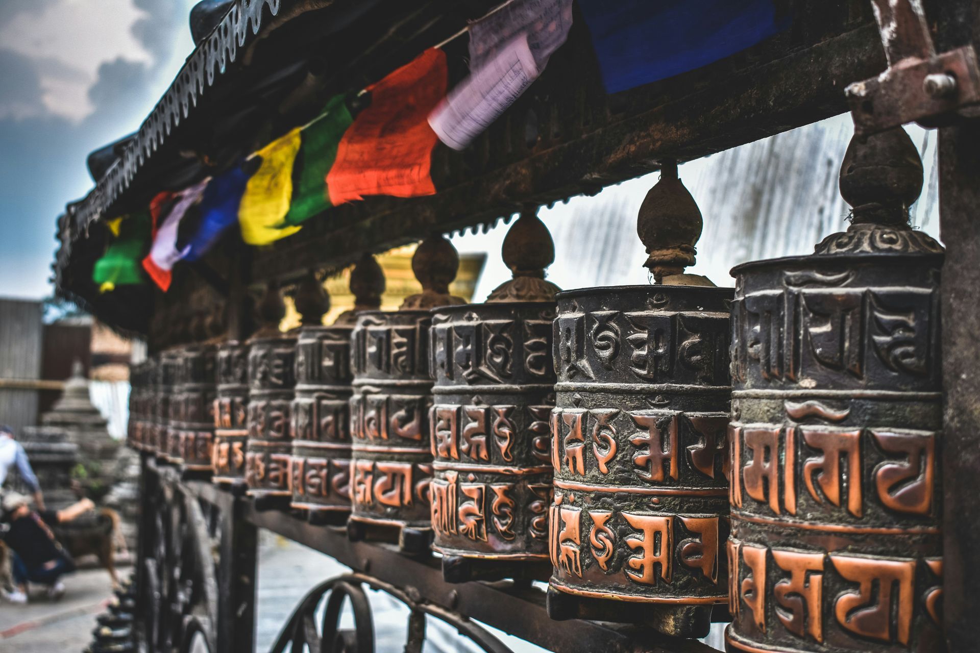 Prayer wheels with colorful prayer flags in a row, Kathmandu, Nepal.