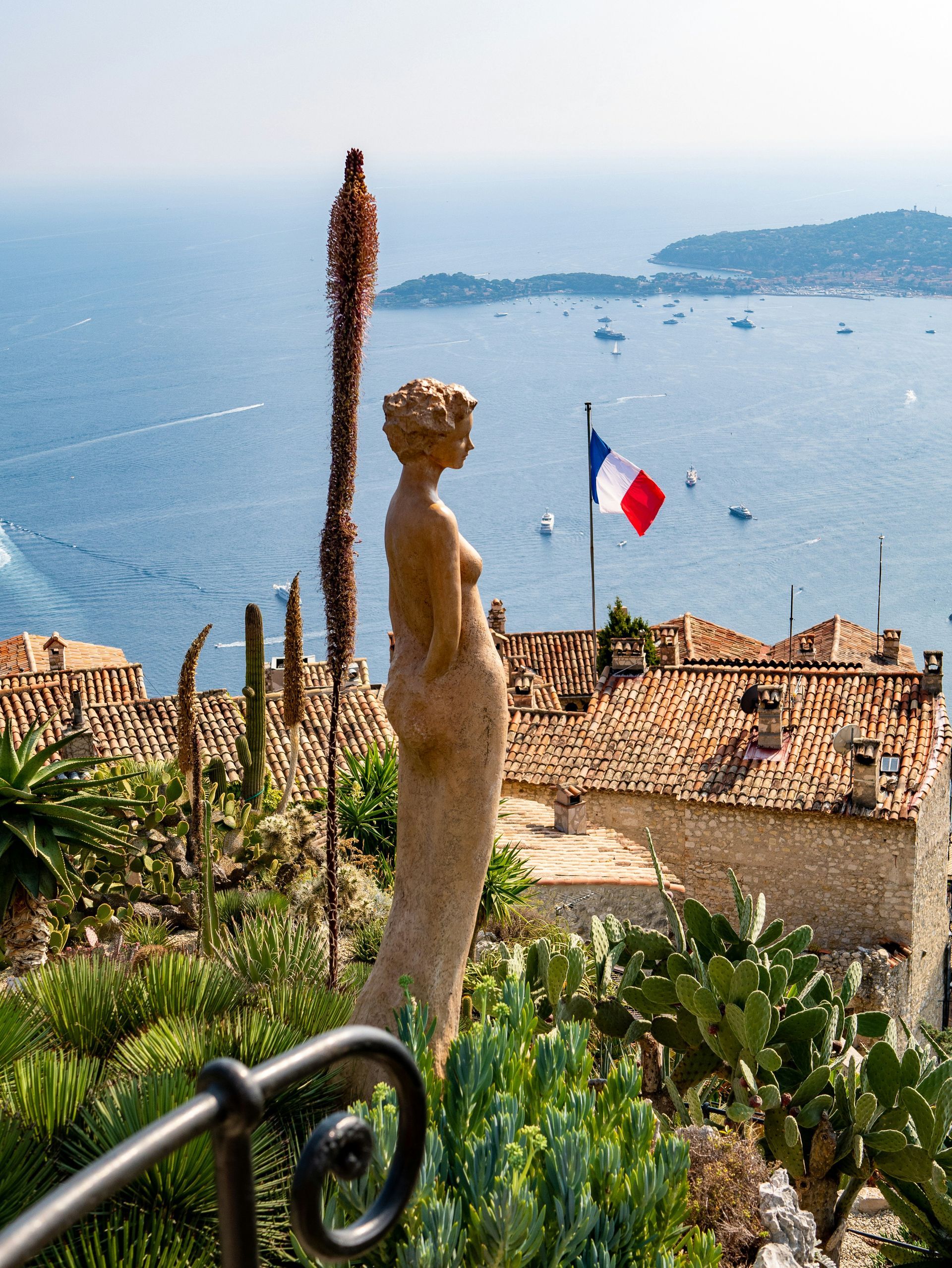 A statue of a woman stands in front of the French Riviera in Èze, France.