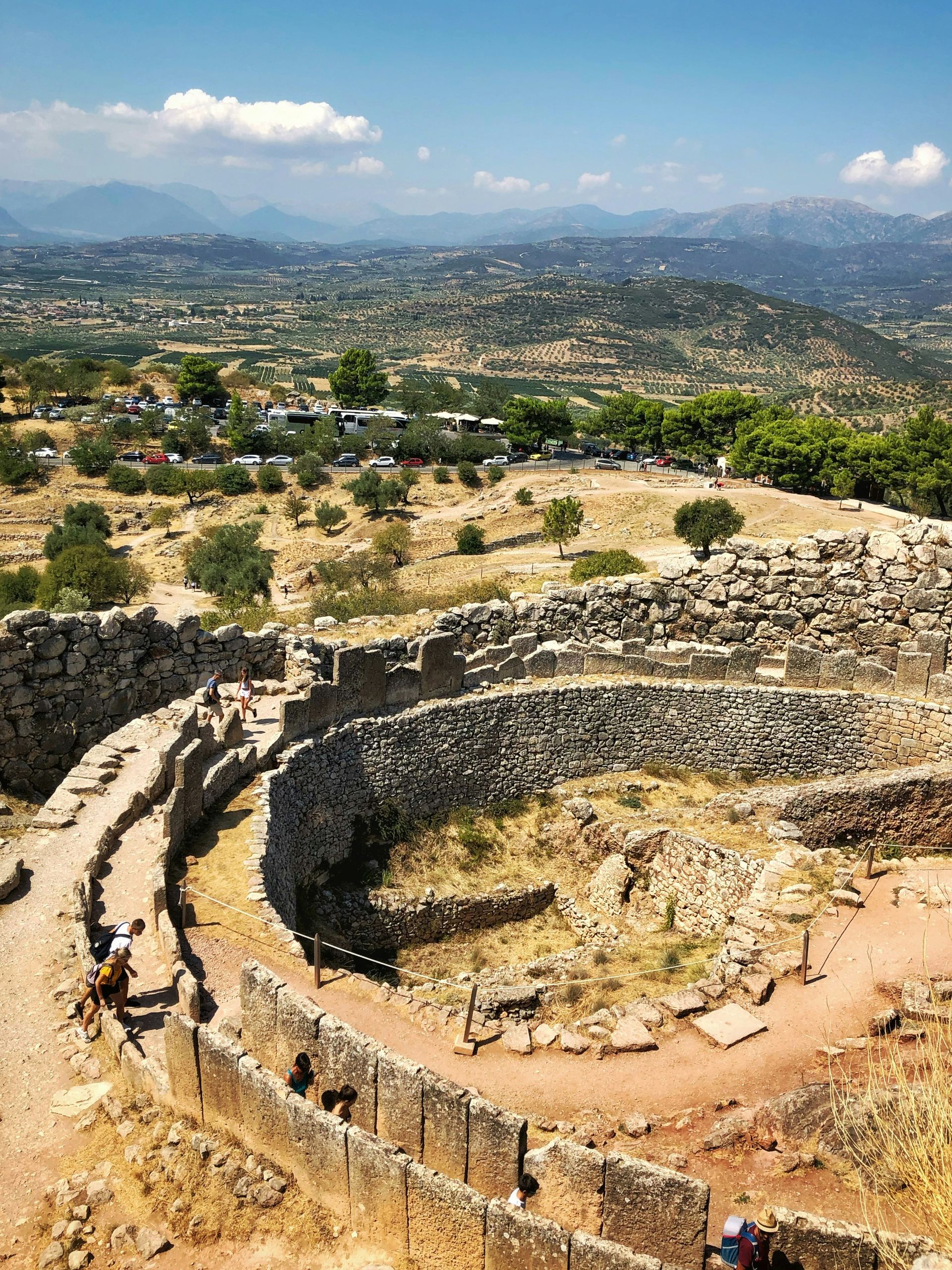 A group of people are standing on top of a stone wall in Mycenae, Greece.