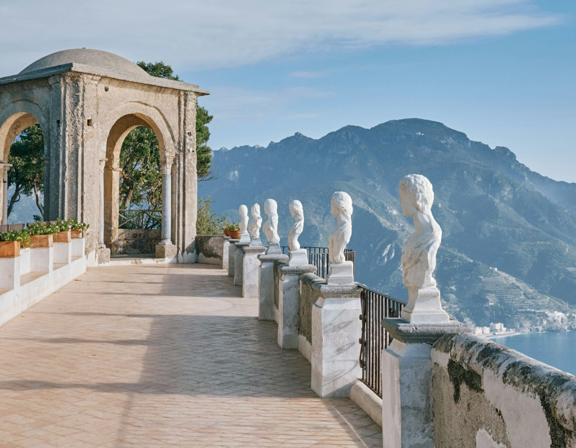 A row of statues on a balcony overlooking a mountain range on Lake Como, Italy.