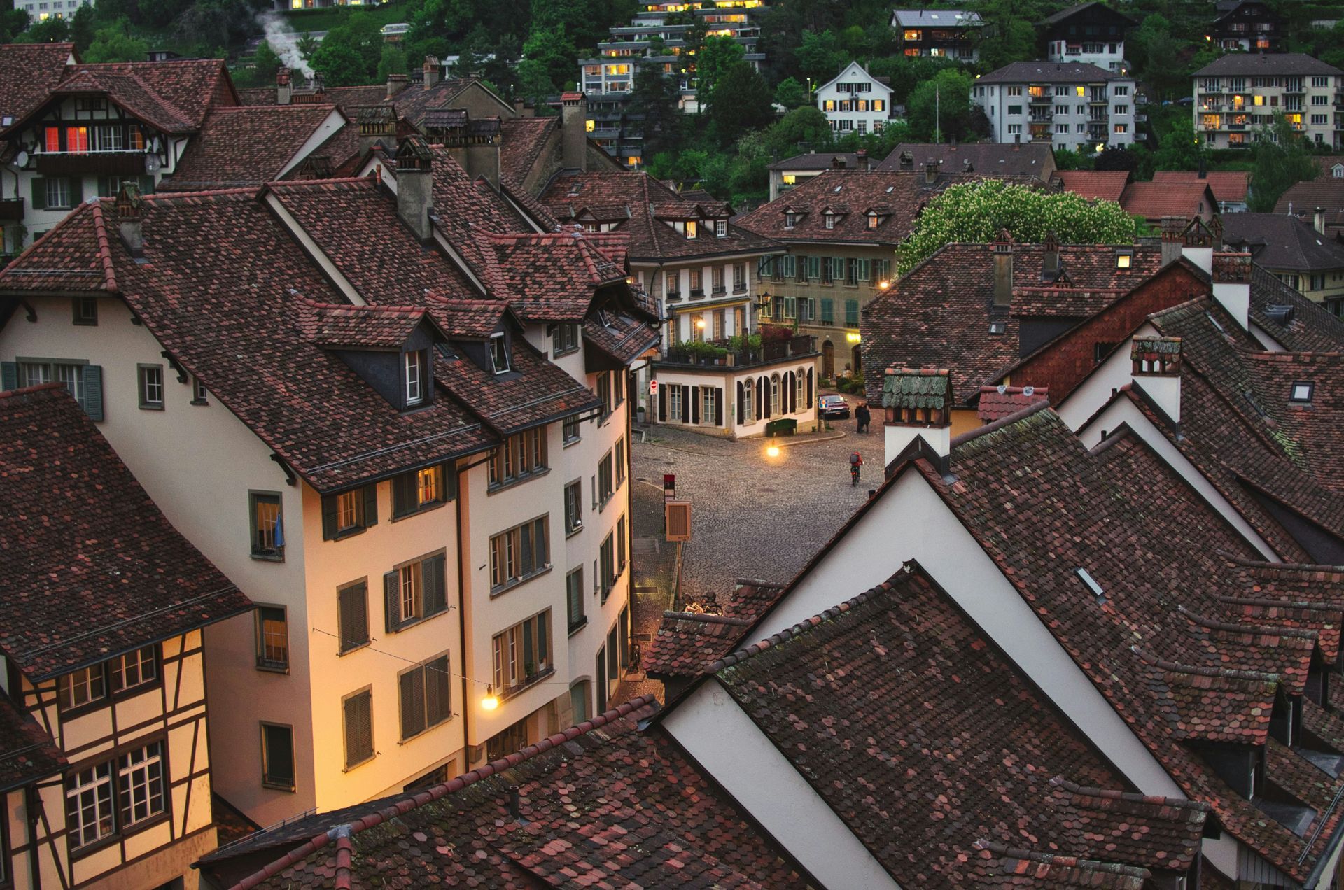 Rooftops of old buildings in Bern, Switzerland at dusk. Tile roofs, soft light on stone buildings, hillside setting.