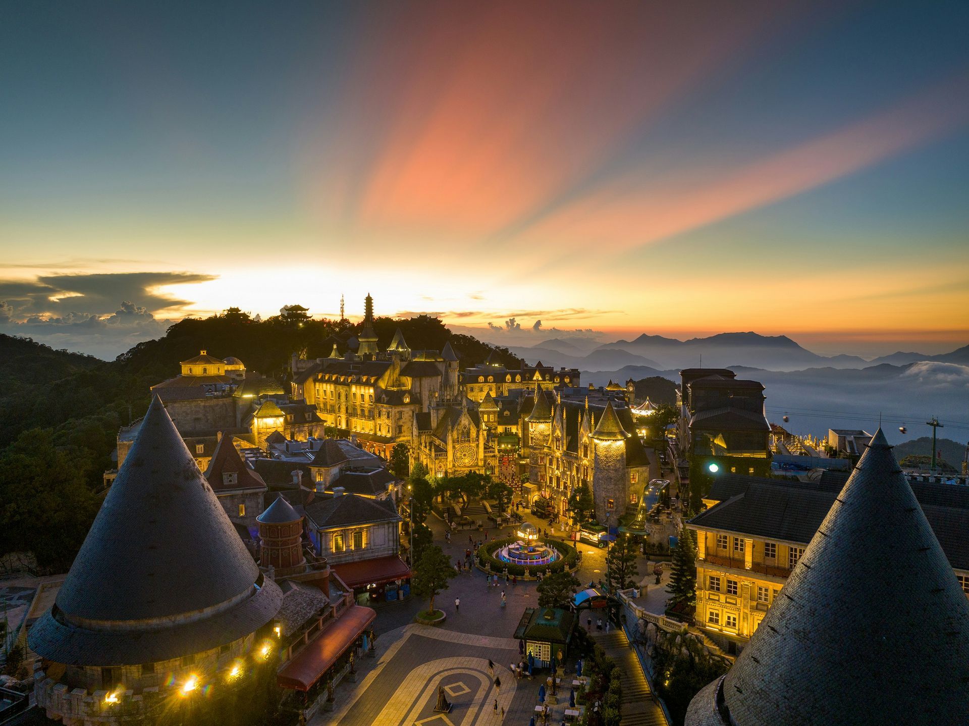 City lit up at dusk with sunset sky and mountain backdrop, in Da Nang, Vietnam.