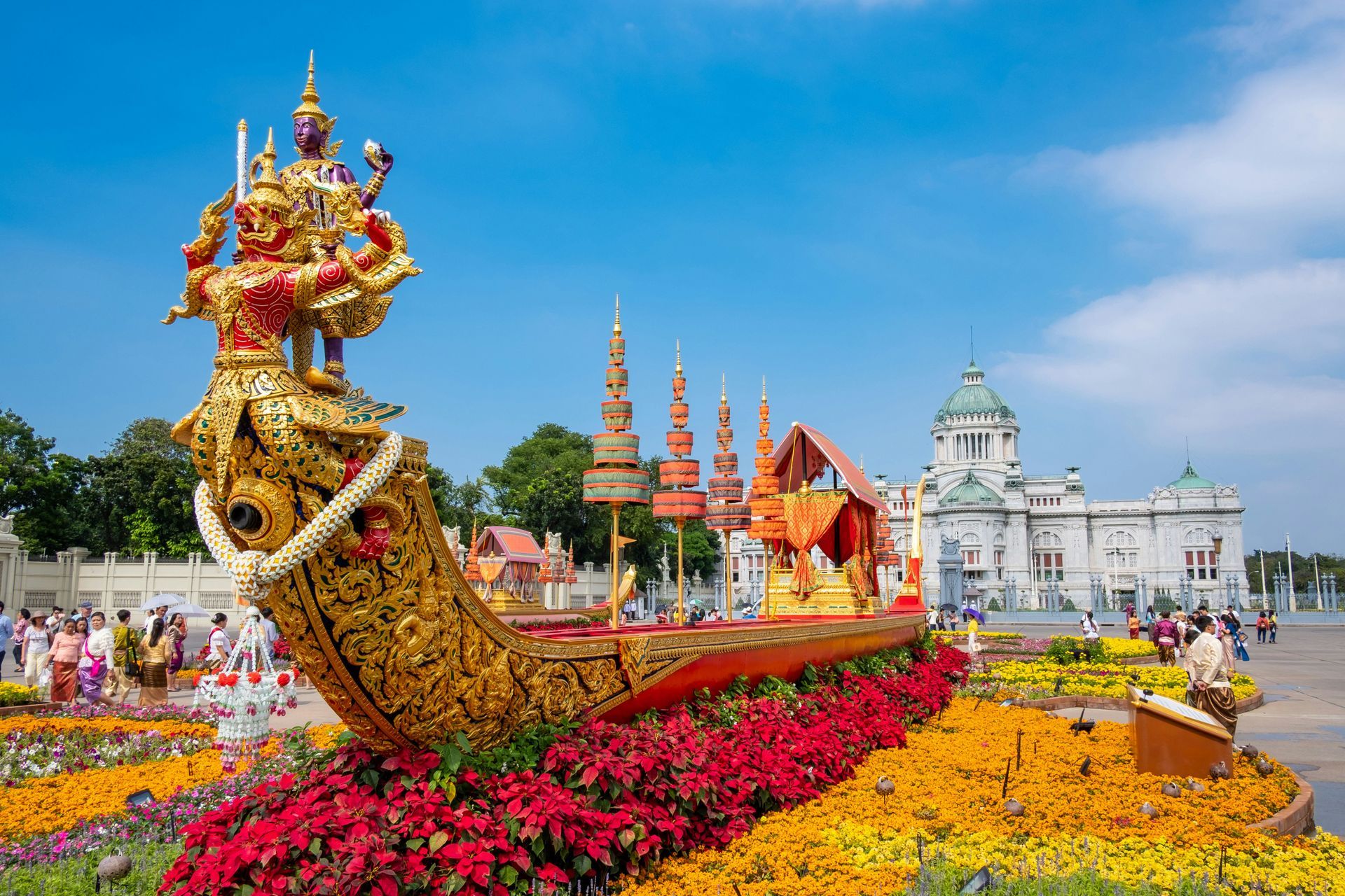 A statue of a dragon is sitting on top of a boat surrounded by flowers in Bangkok, Thailand.
