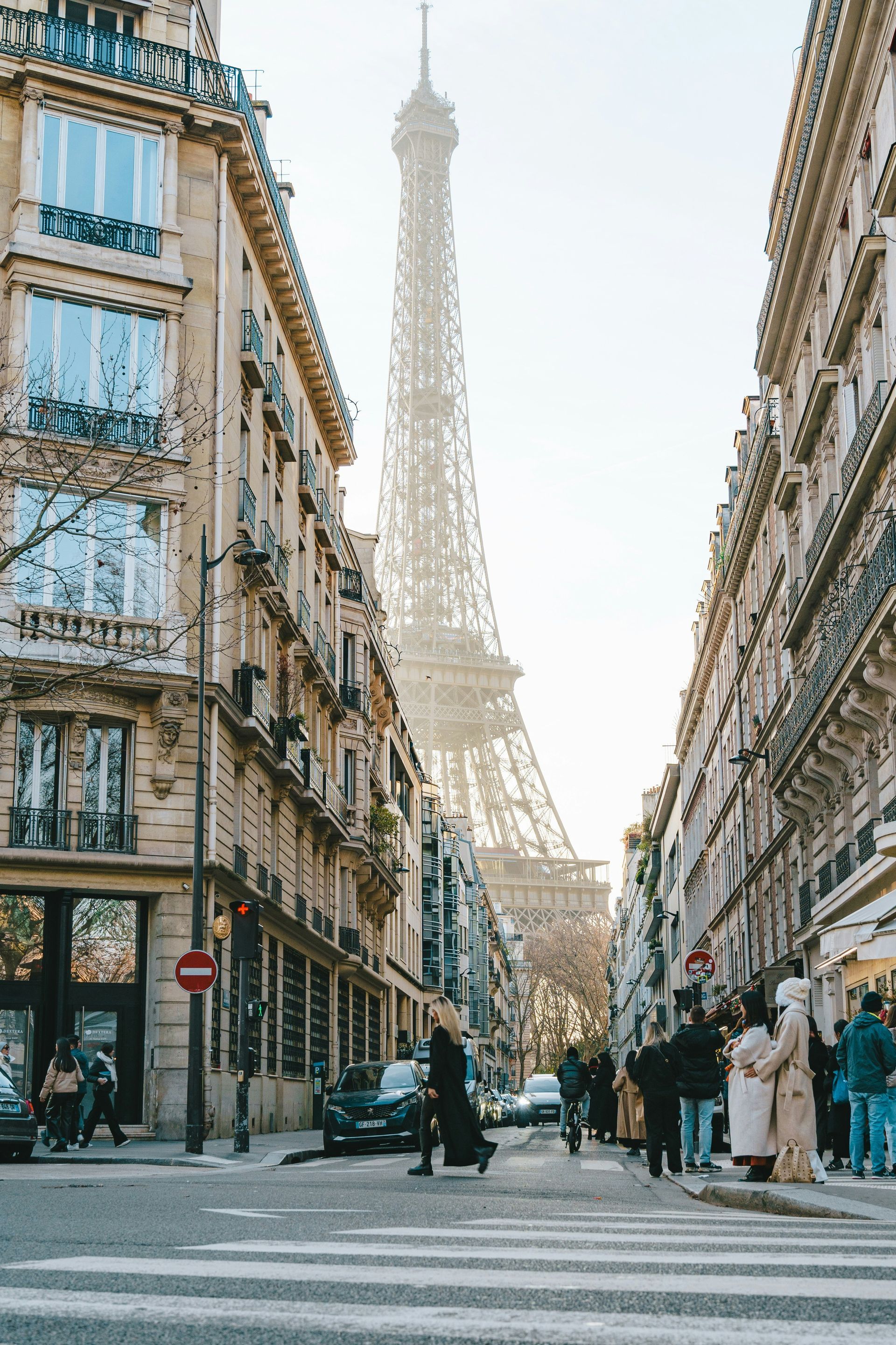 The eiffel tower is visible in the background of a city street in Paris, France.