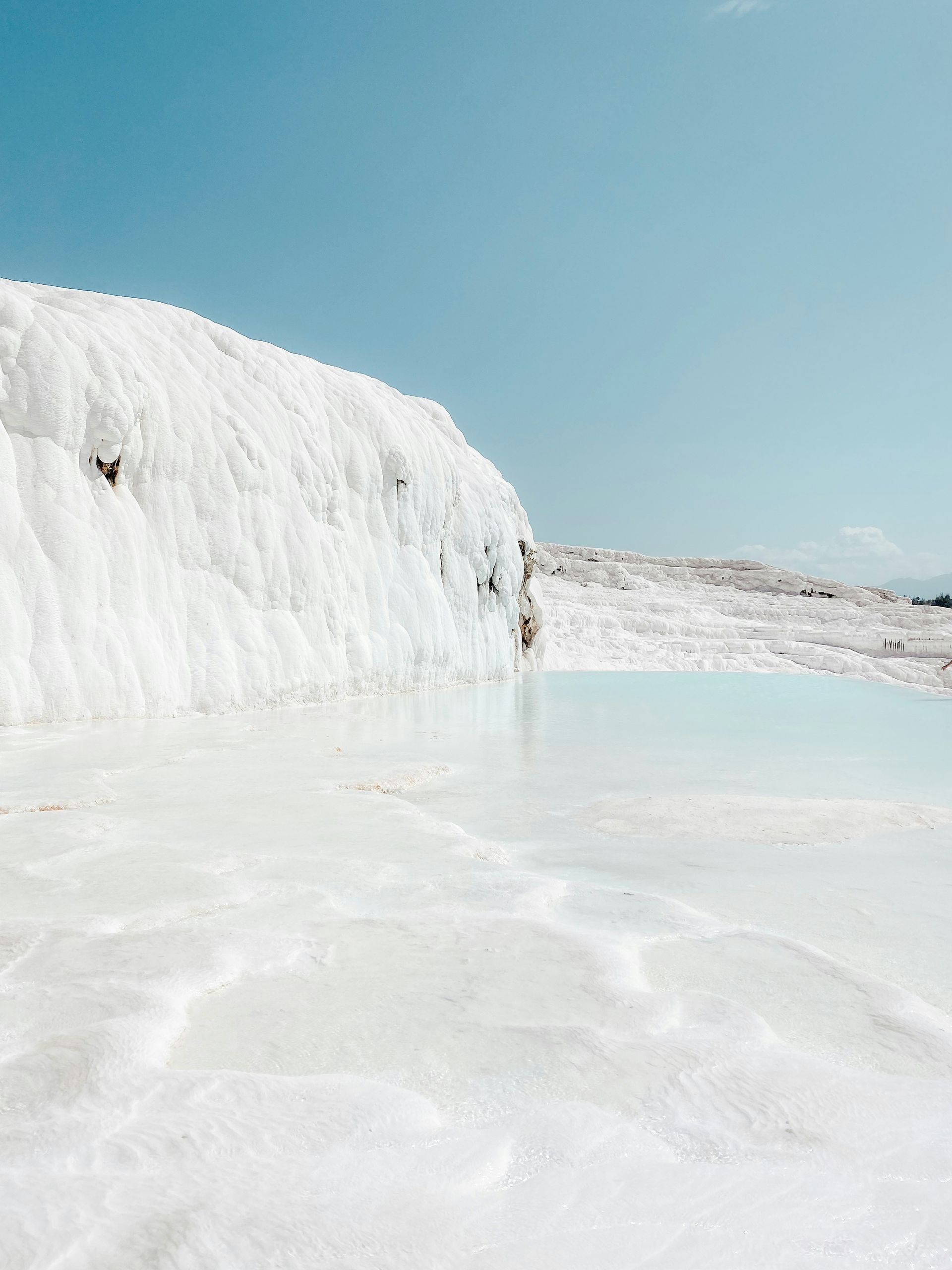 White travertine terraces with turquoise water against a clear blue sky, Pamukkale, Turkey.
