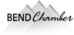 A black and white logo for bend chamber with mountains in the background.