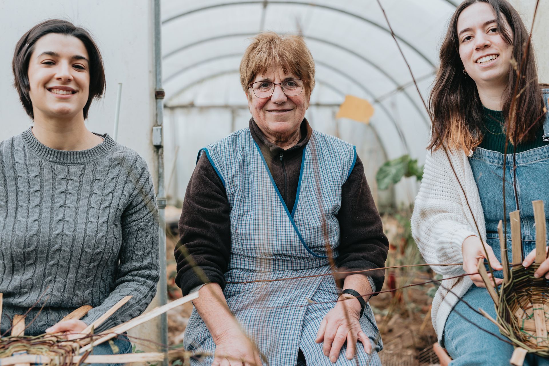 Three women are posing for a picture in a greenhouse.