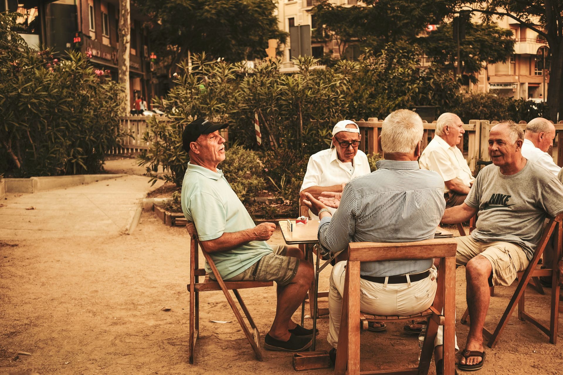A group of men are sitting around a table in a park.