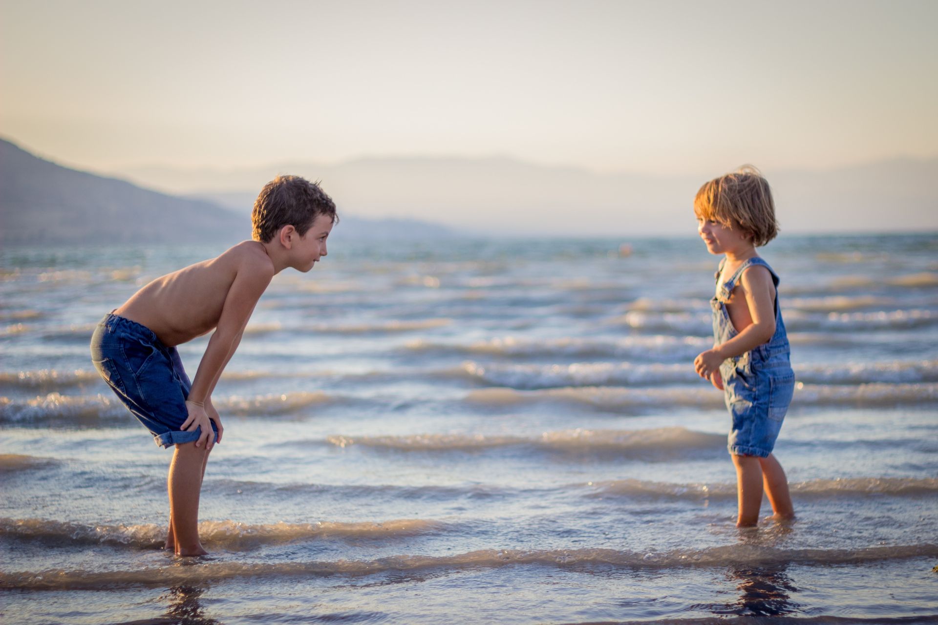 Two young boys are playing in the water on the beach.