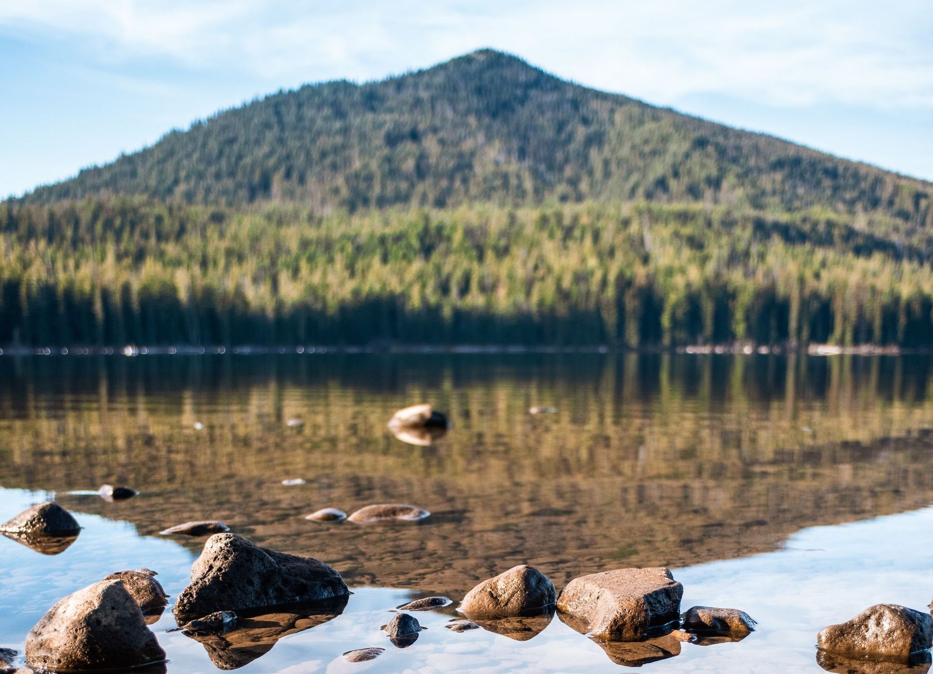 A lake with a mountain in the background and rocks in the foreground.