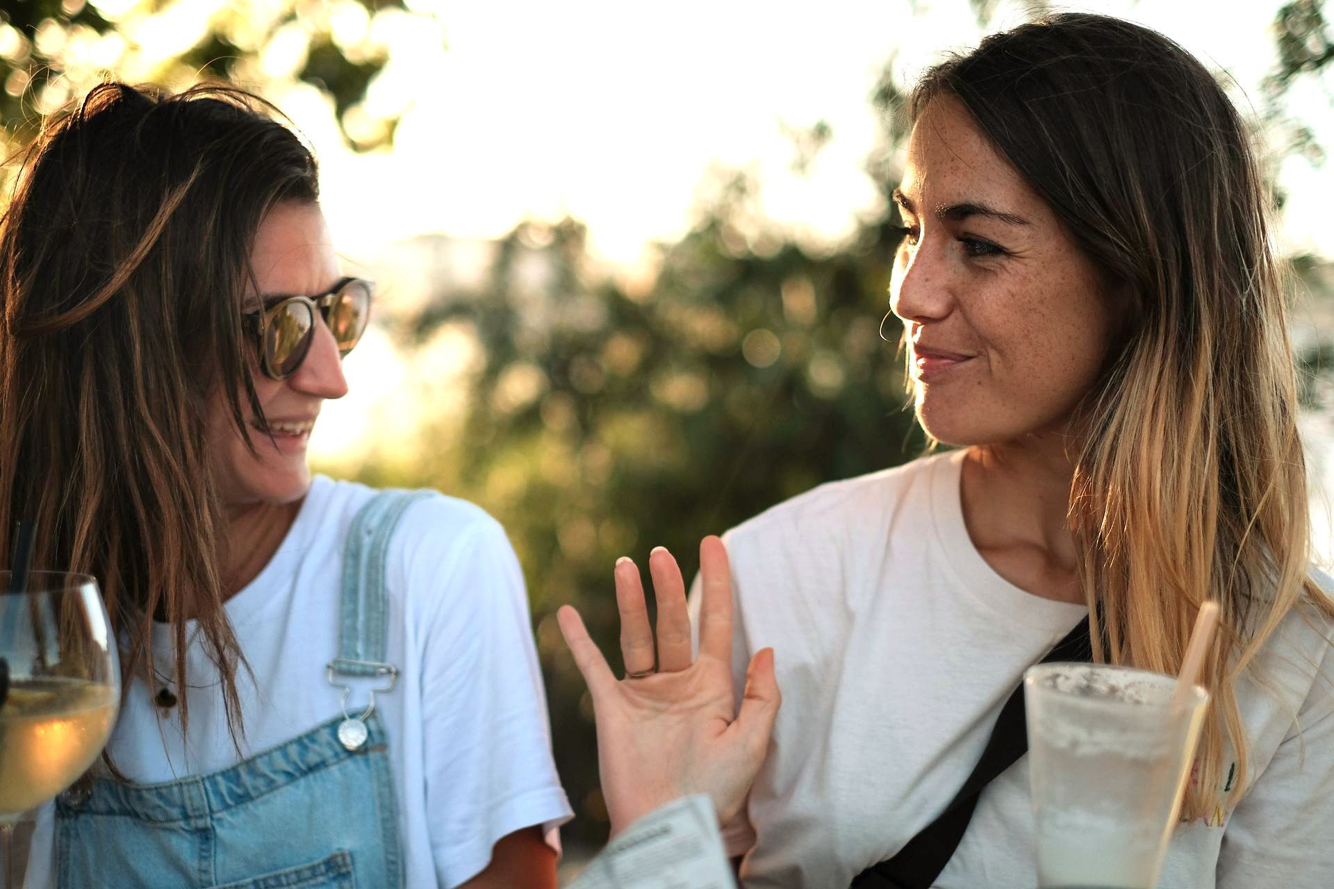 Two women are sitting next to each other drinking wine and talking.