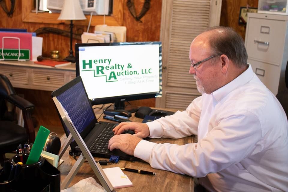 A man in a white button-down shirt works on a laptop at a desk in an office with a 