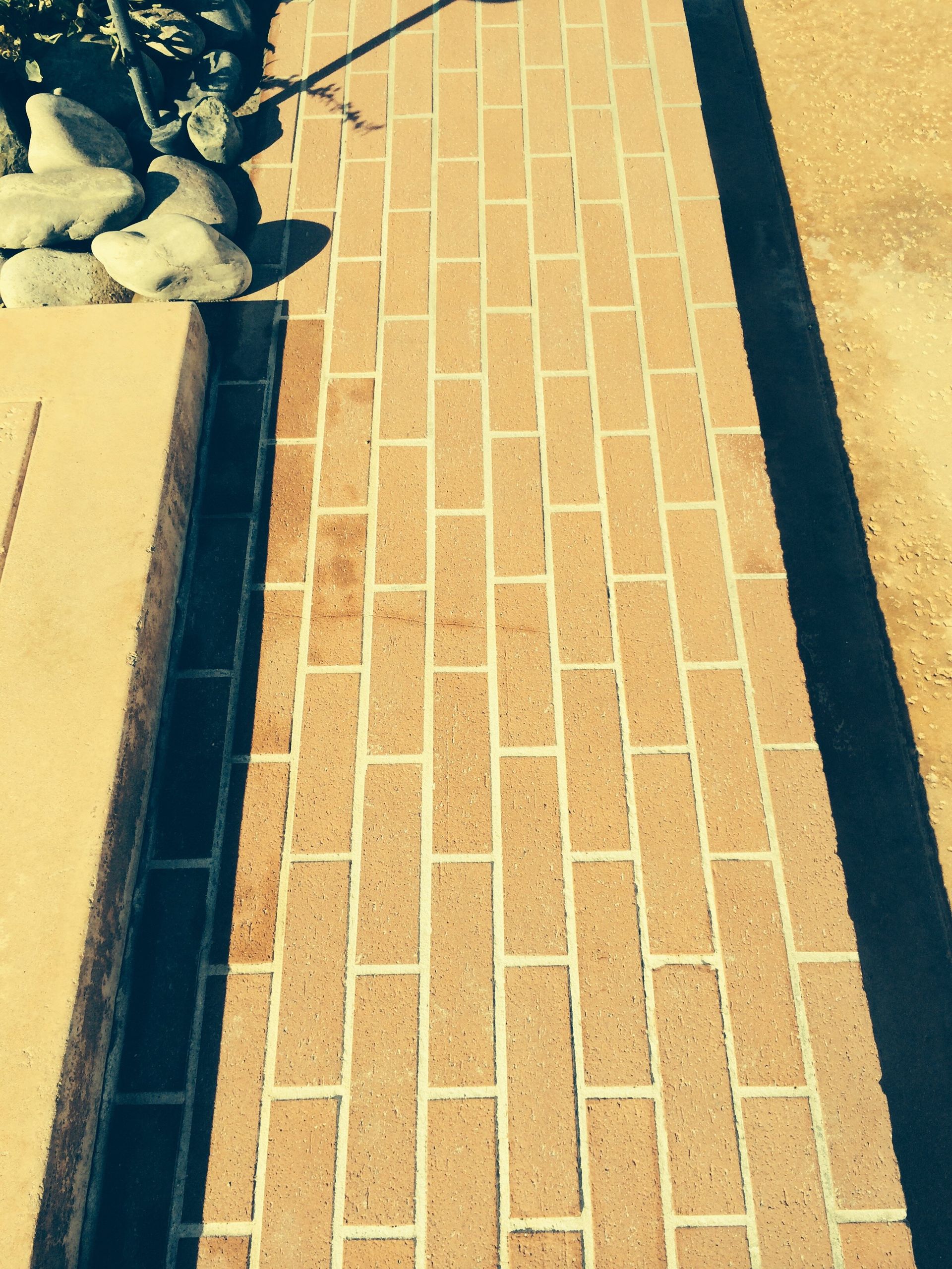 A brick walkway with a shadow on the ground