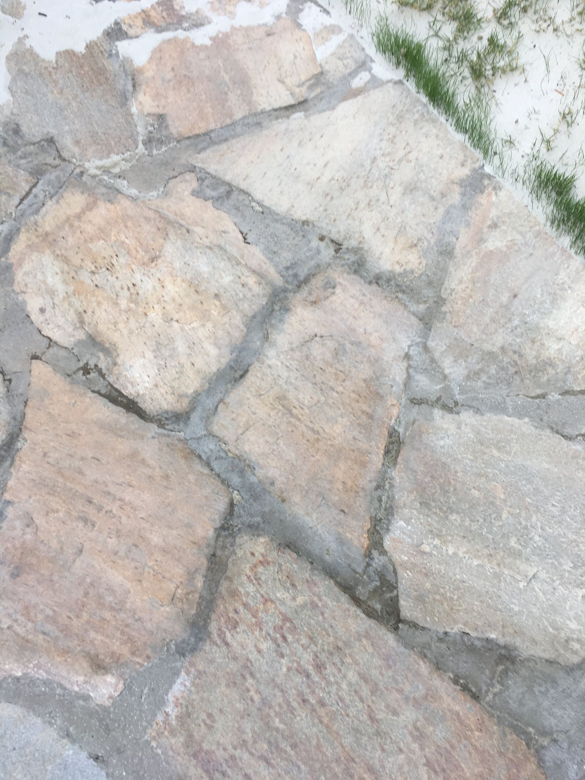 A close up of a stone walkway with grass in the background