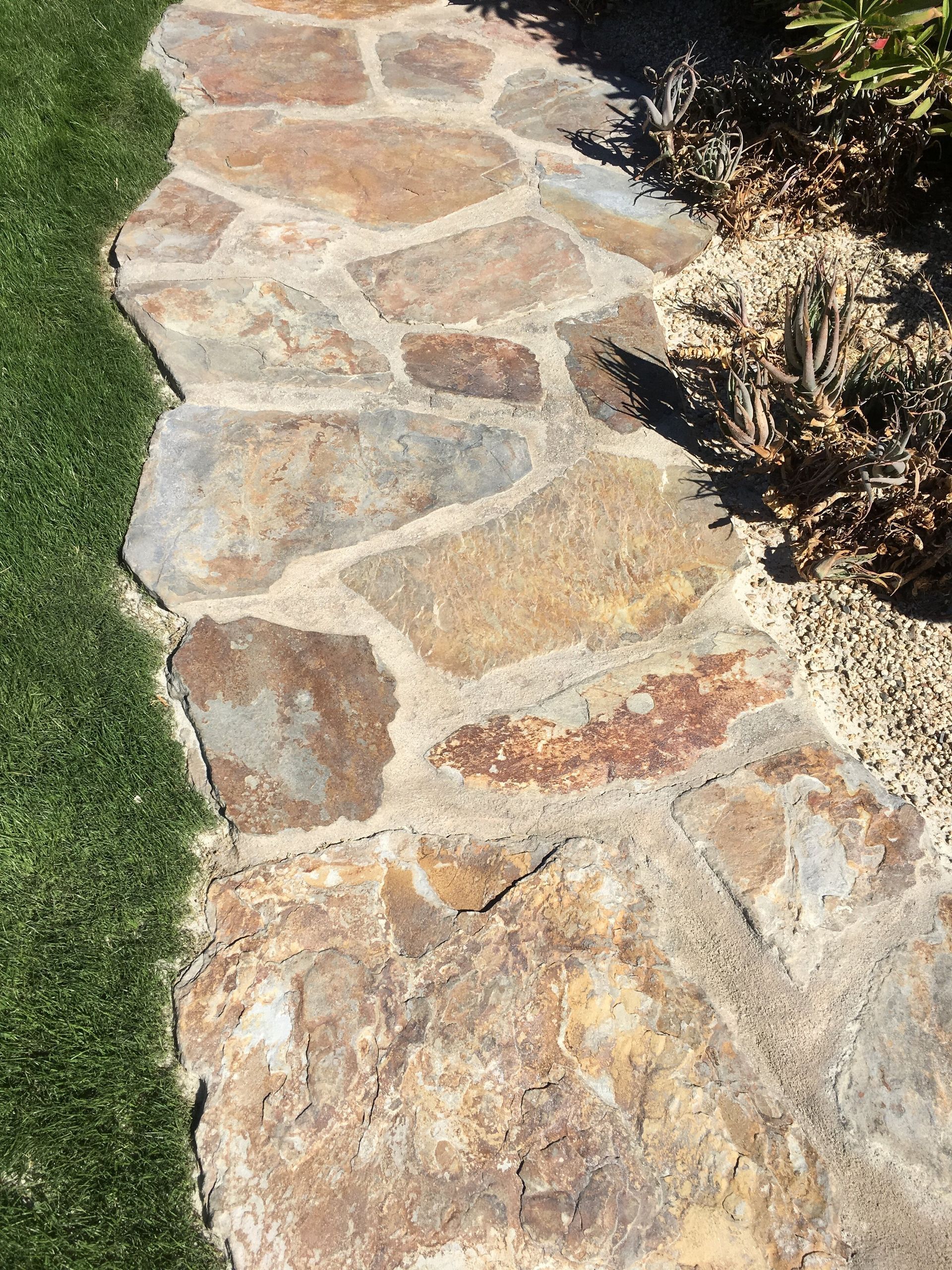 A stone walkway going through a lush green field.