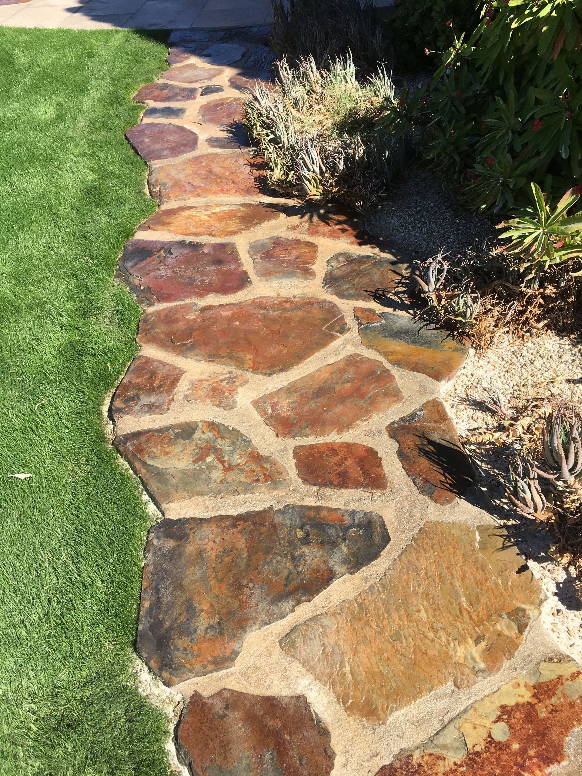 A stone walkway leading to a lush green lawn.
