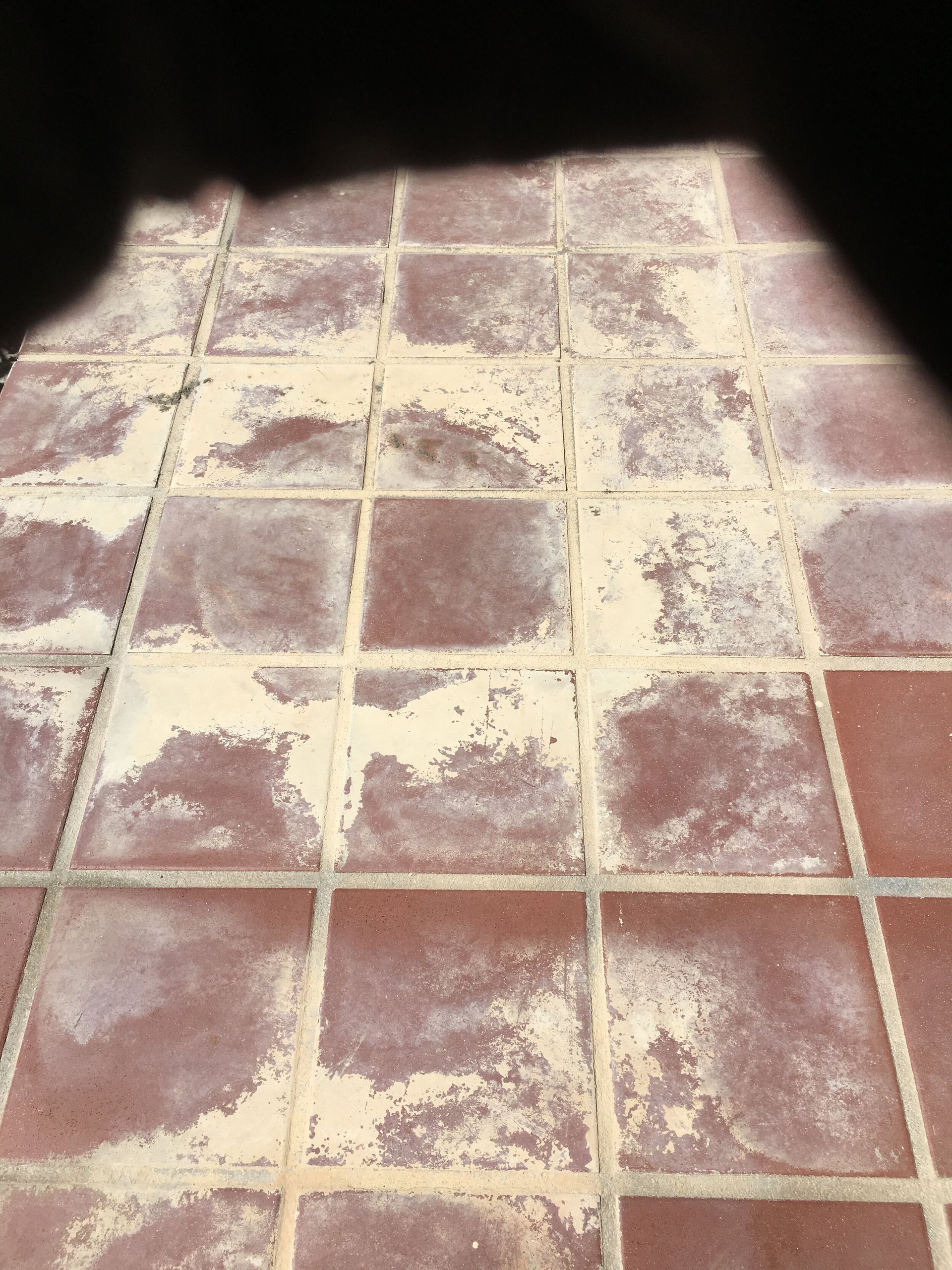 A close up of a tiled floor with a shadow on it.