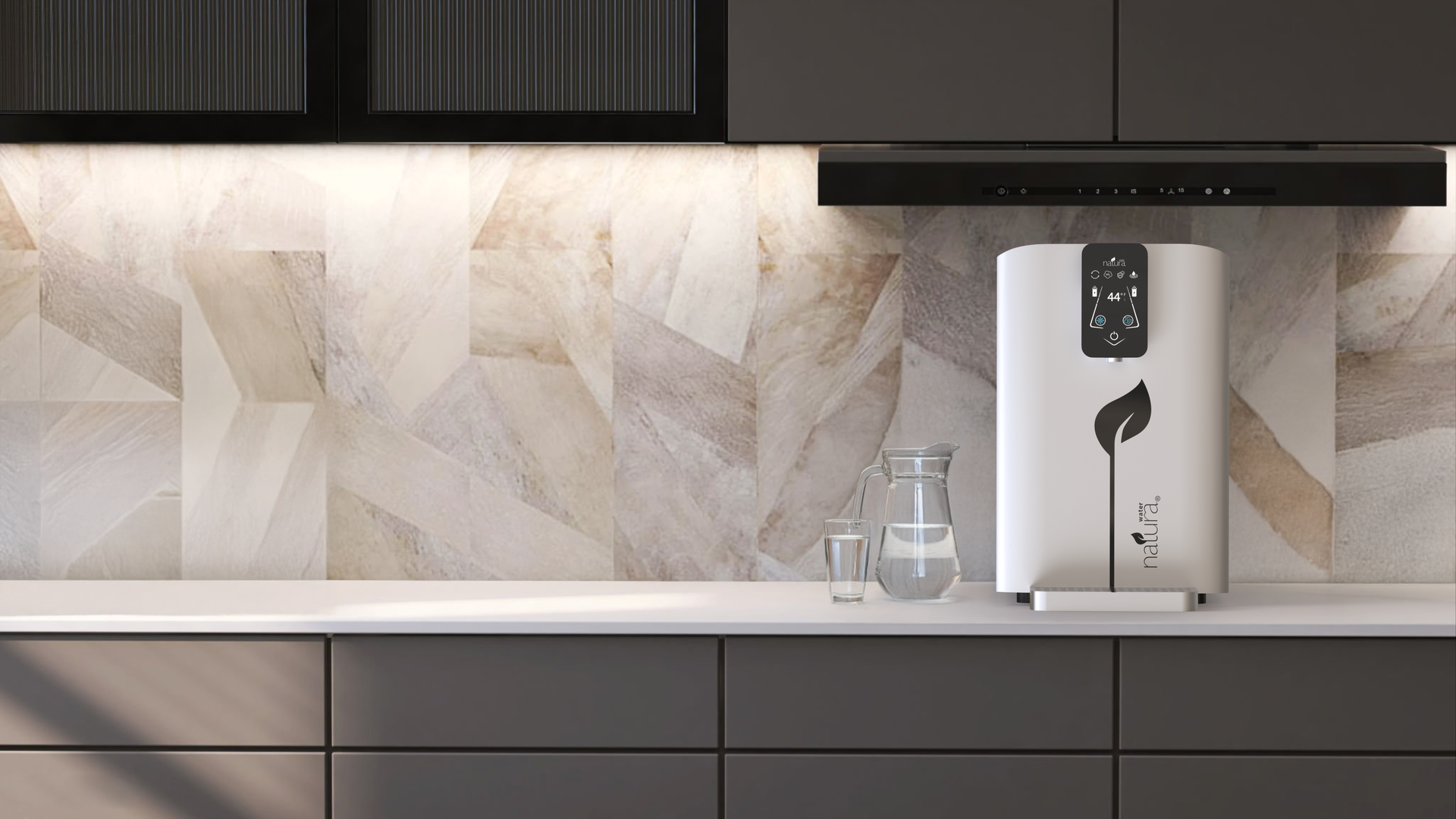 White water purifier on a kitchen counter, beside a glass of water and pitcher.