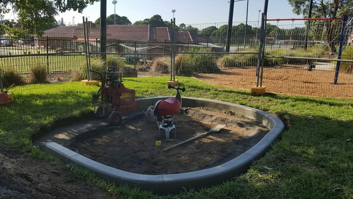 There is a sandbox in the middle of the grass in a park.