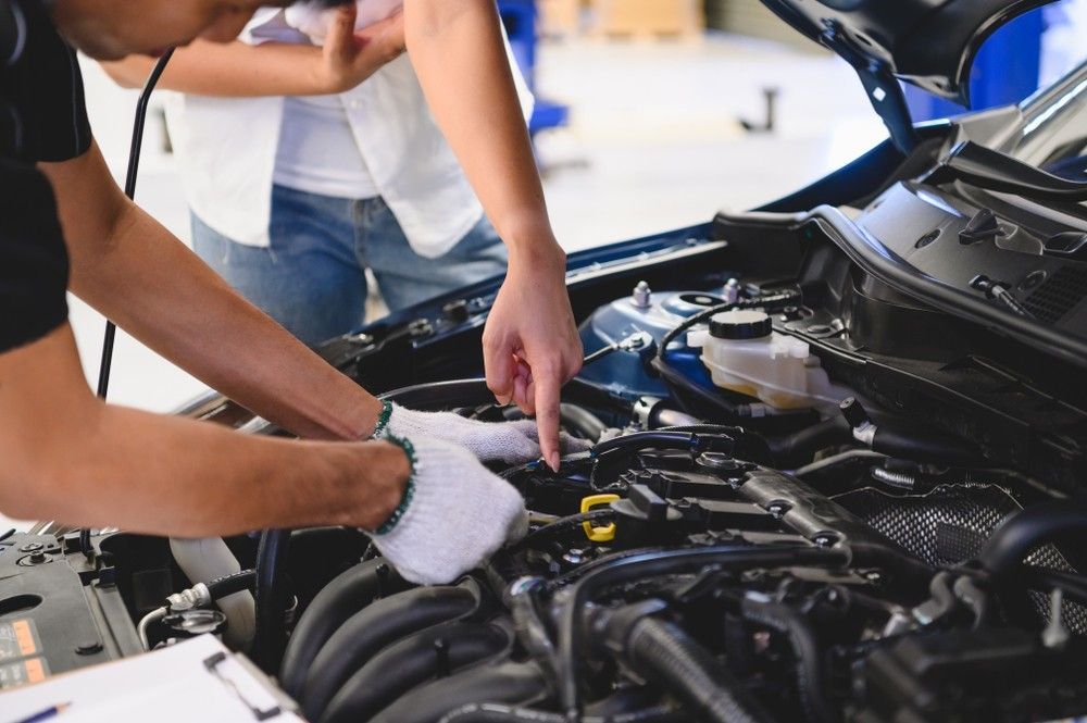 A Man And A Woman Are Working On The Engine Of A Car — Bay City Quality Mobile Mechanic In Pialba, QLD