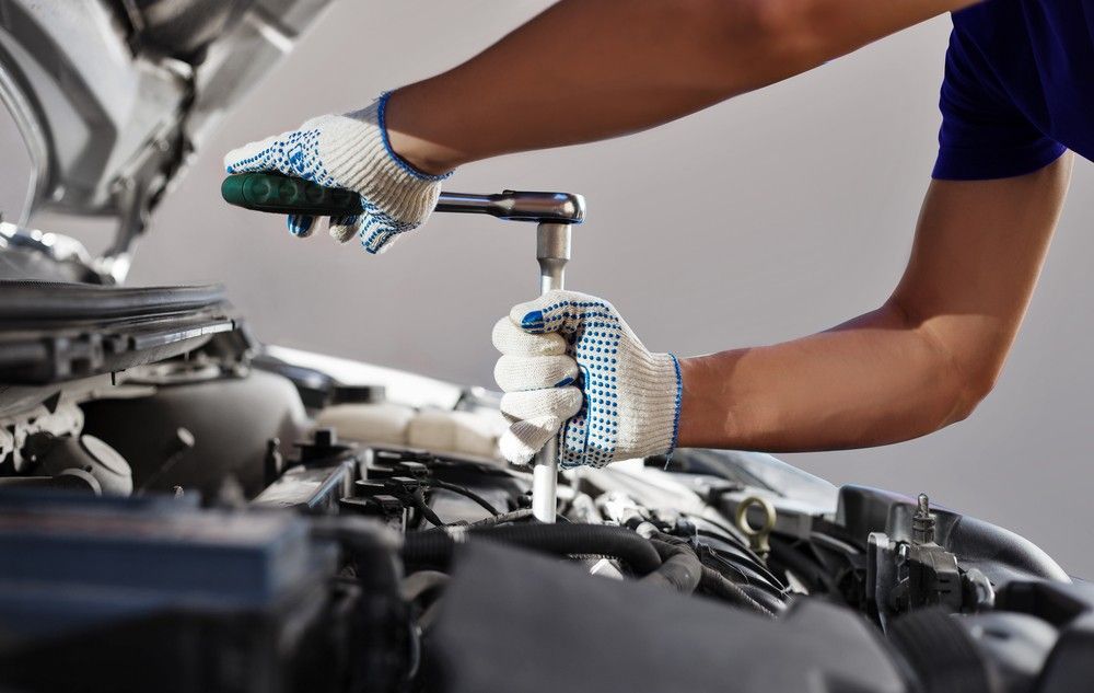 A Man Is Working On The Engine Of A Car With A Wrench — Bay City Quality Mobile Mechanic In Pialba, QLD