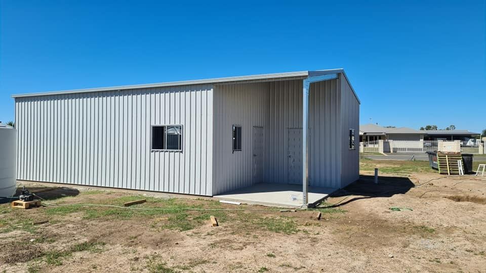 A White Metal Building With A Porch In The Middle Of A Field — Bushman Sheds in Bundaberg East, QLD