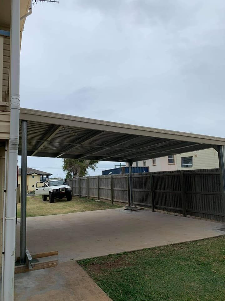 A Car Is Parked Under A Carport In Front Of A House — Bushman Sheds in Bundaberg East, QLD