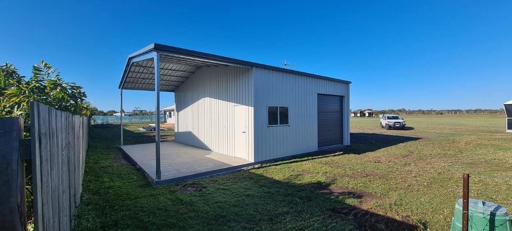A Small White Shed With A Covered Porch In The Middle Of A Field — Bushman Sheds in Bundaberg East, QLD