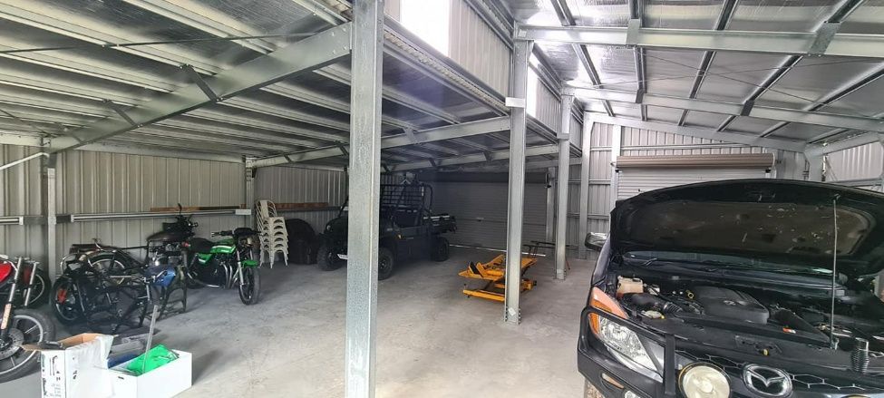 A Car Is Parked In A Garage With Its Hood Open — Bushman Sheds in Bundaberg East, QLD