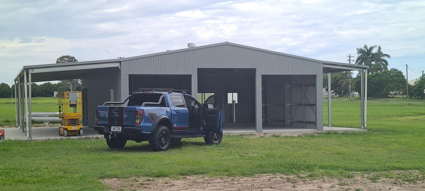 A Blue Truck Is Parked In Front Of A Large Building — Bushman Sheds in Bundaberg East, QLD