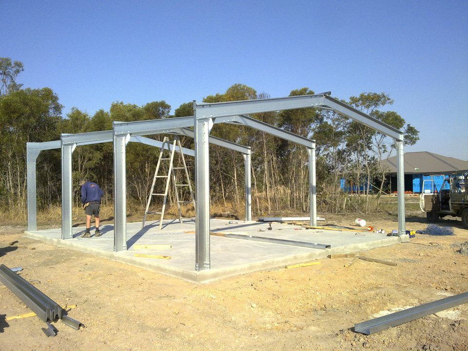A Metal Structure Is Being Built In A Dirt Field — Bushman Sheds in Bundaberg East, QLD