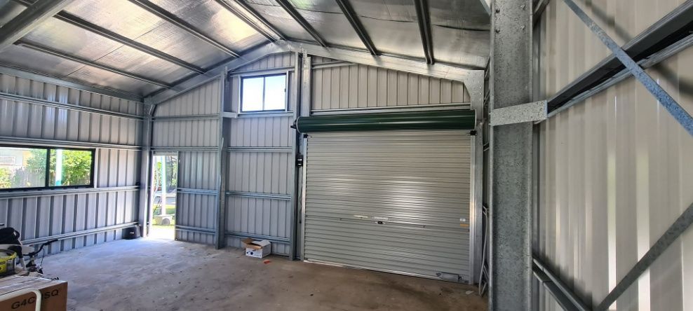 An Empty Garage With A Garage Door And A Window — Bushman Sheds in Bundaberg East, QLD