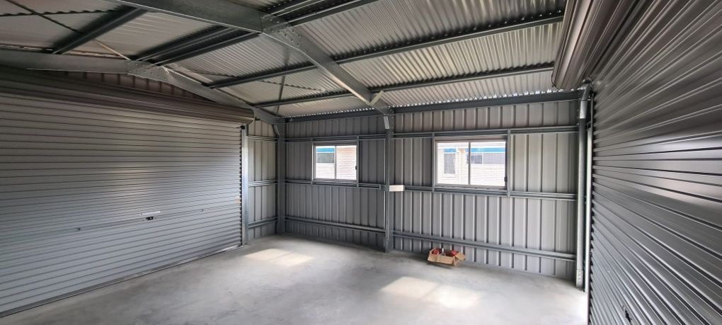 An Empty Garage With A Metal Roof And A Concrete Floor — Bushman Sheds in Bundaberg East, QLD