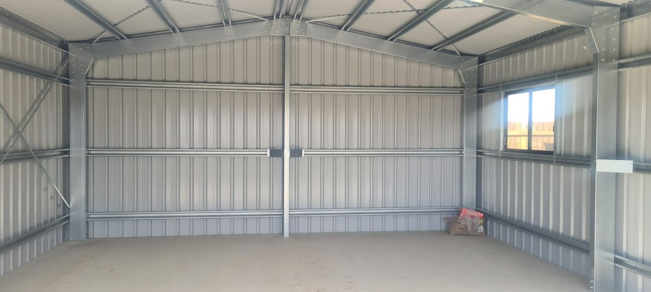 The Inside Of An Empty Metal Shed With A Window — Bushman Sheds in Bundaberg East, QLD