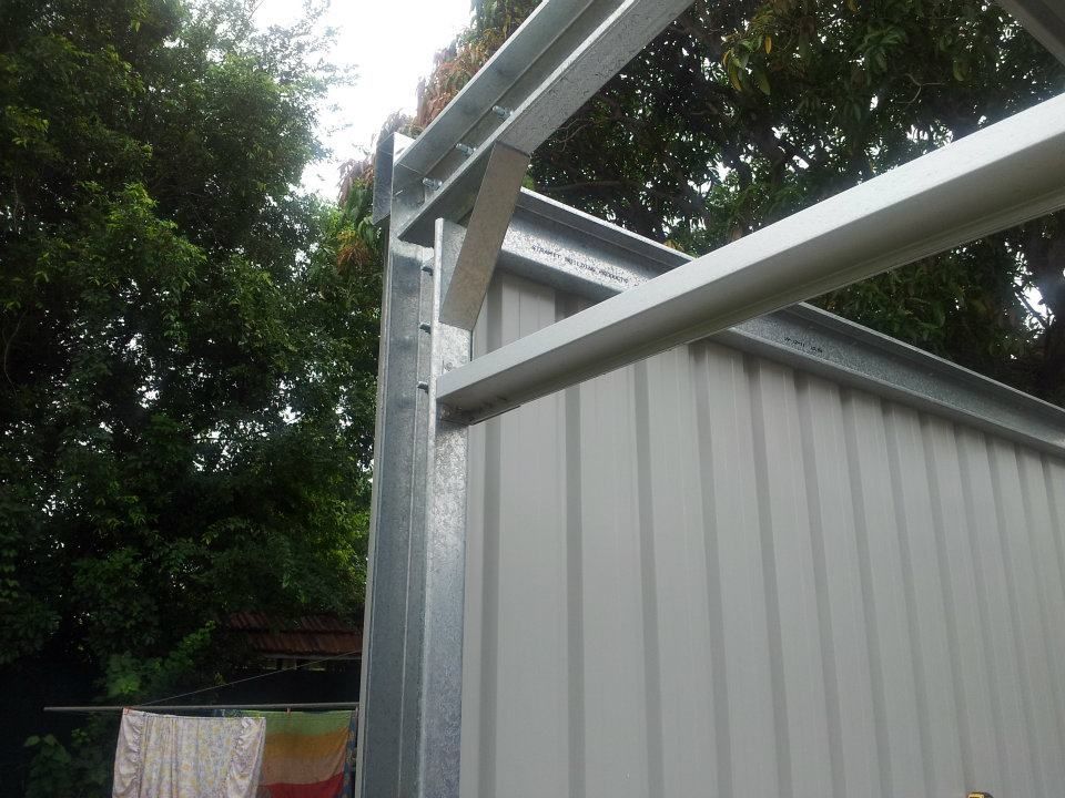 A Close Up Of A Metal Structure With A White Wall And Trees In The Background — Bushman Sheds in Bundaberg East, QLD