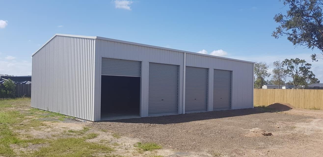 A Large White Metal Shed With A Fence In The Background — Bushman Sheds in Bundaberg East, QLD