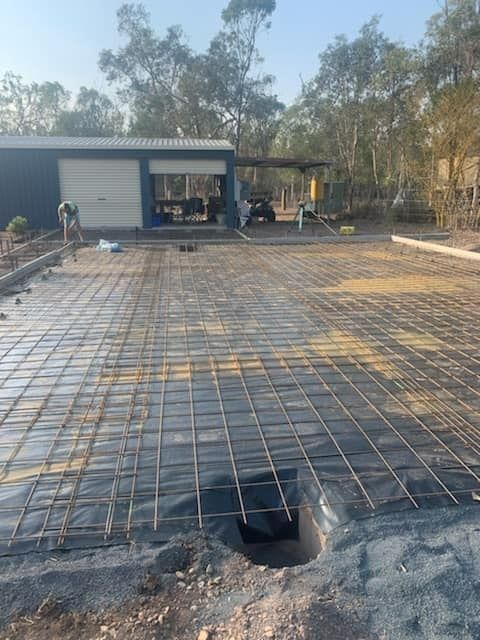 A Concrete Driveway Is Being Built In Front Of A House — Bushman Sheds in Bundaberg East, QLD