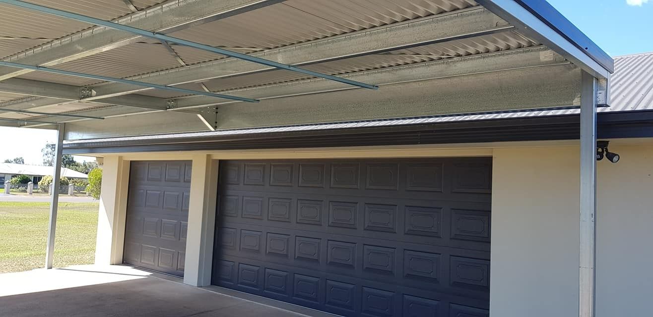 A Garage With A Canopy Over It And A Black Garage Door — Bushman Sheds in Bundaberg East, QLD