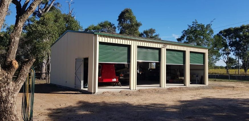 A Garage With A Red Car Parked Inside Of It — Bushman Sheds in Bargara, QLD
