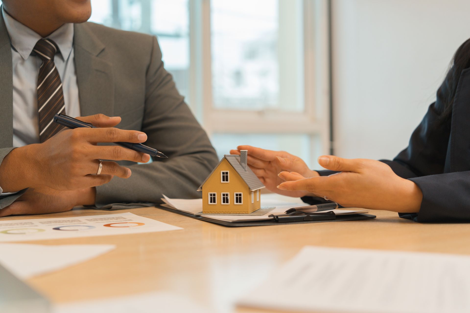 Business meeting with two people discussing a small house model on a table