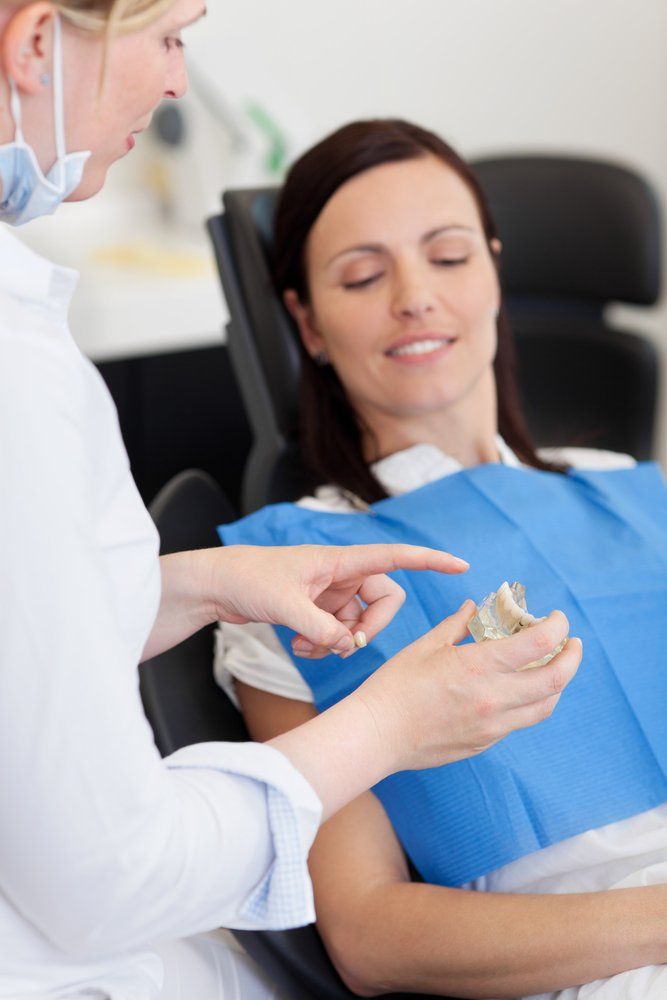 Dentist Explaining To Patient With Tooth Model— Dentistry Services in Cairns, QLD