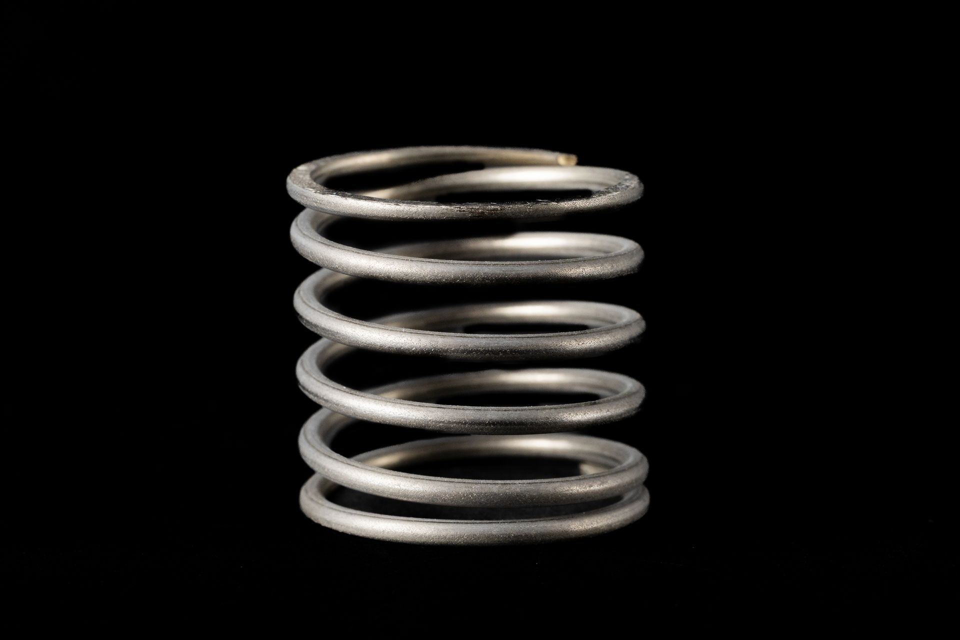 Silver metal spring against a black background.