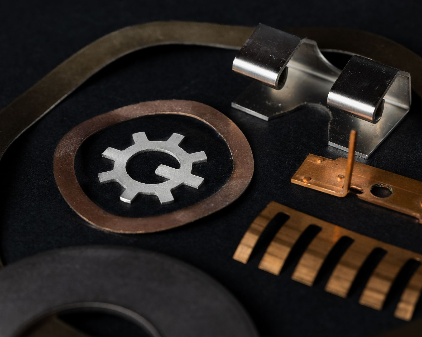 Metal springs and washers in various shapes and colors on a black surface.