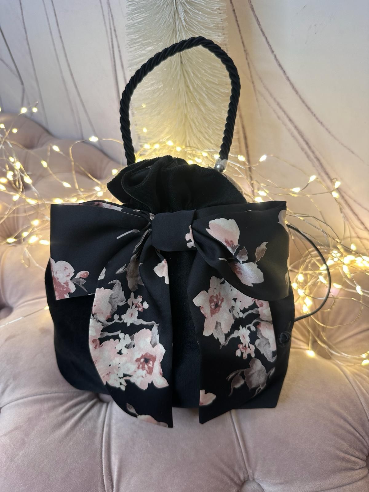 Una borsa nera con dei fiori sopra è appoggiata su un divano