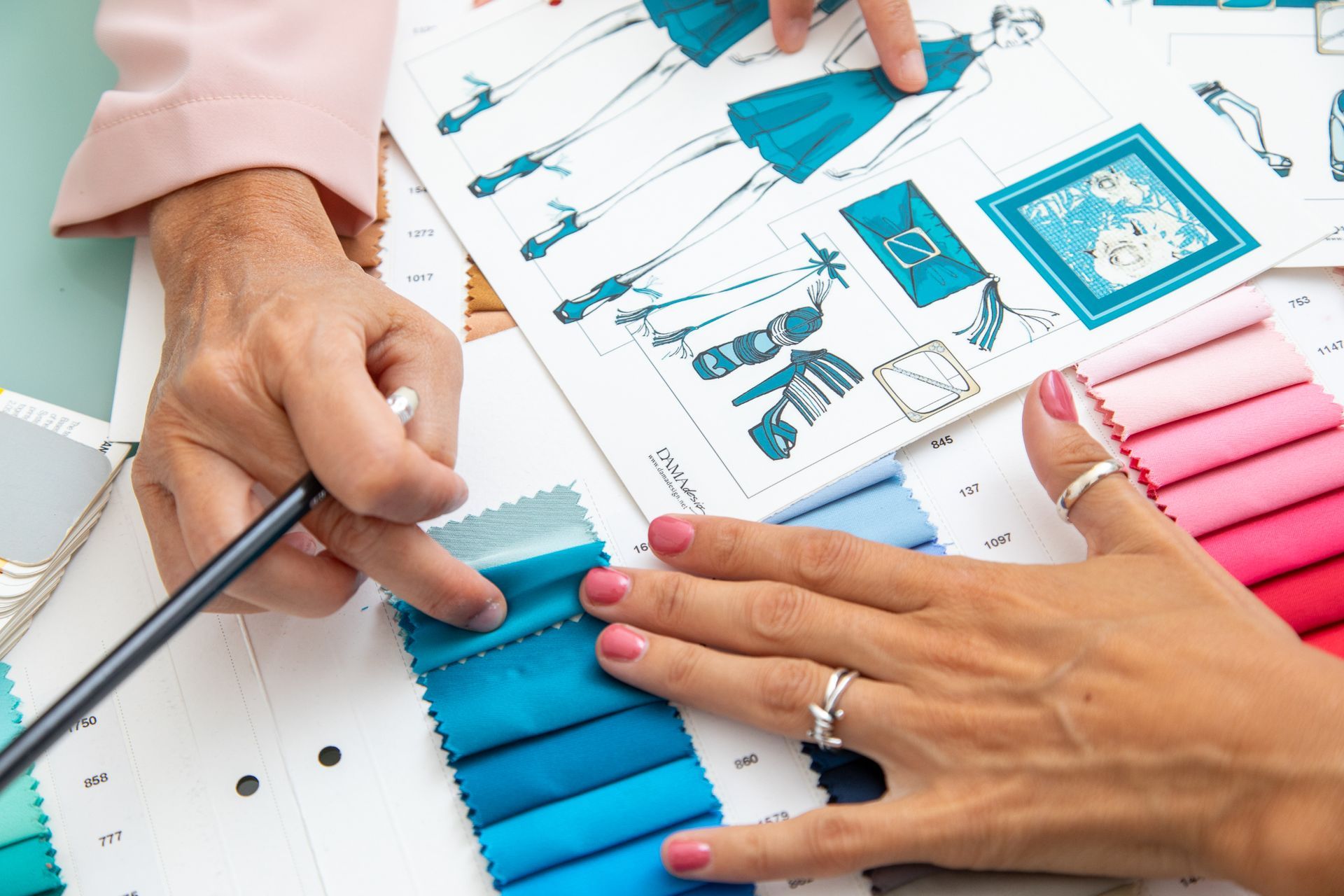 Una donna è seduta a un tavolo e guarda il disegno di un vestito.