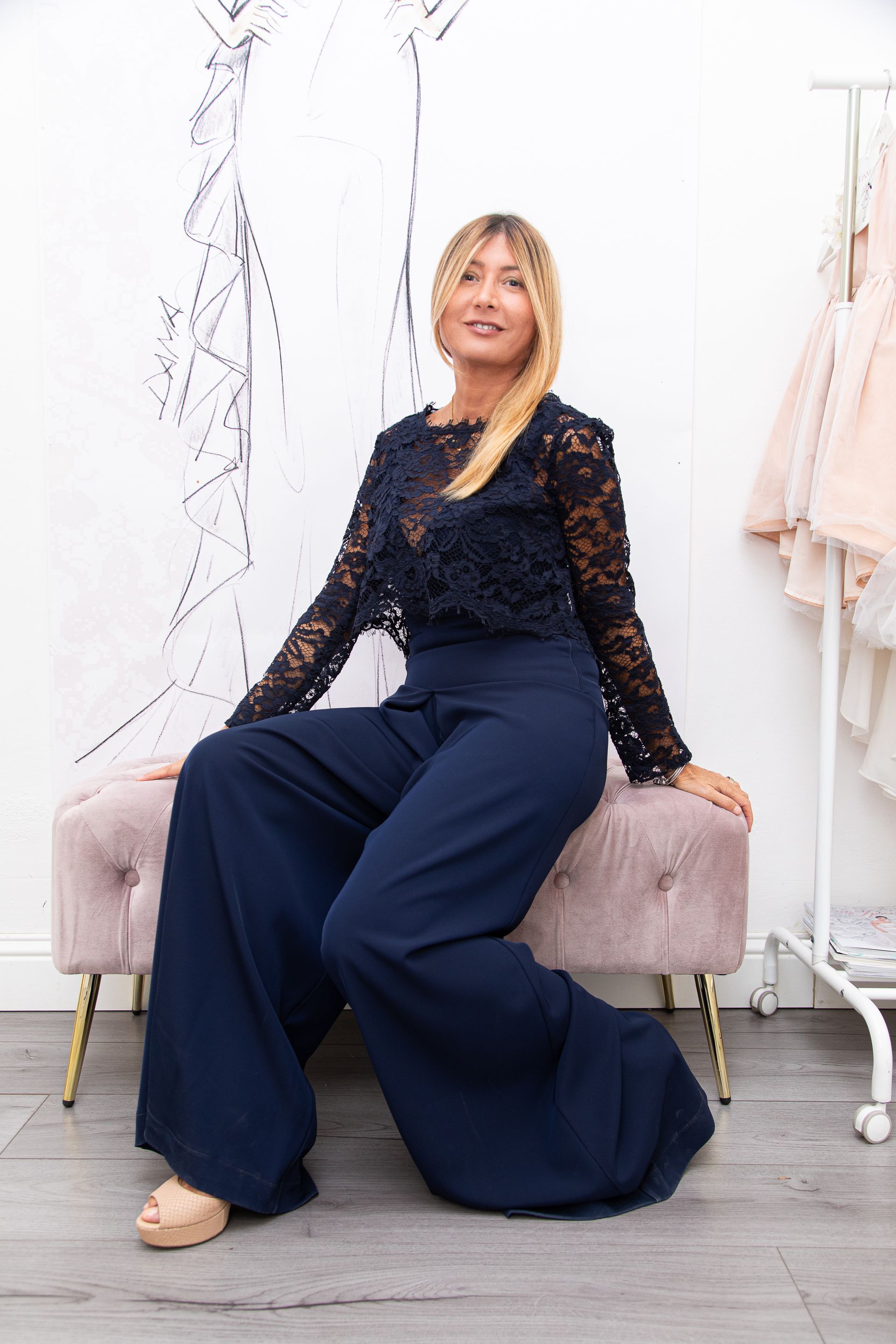 Una donna con un top di pizzo e pantaloni larghi è seduta su una panchina.