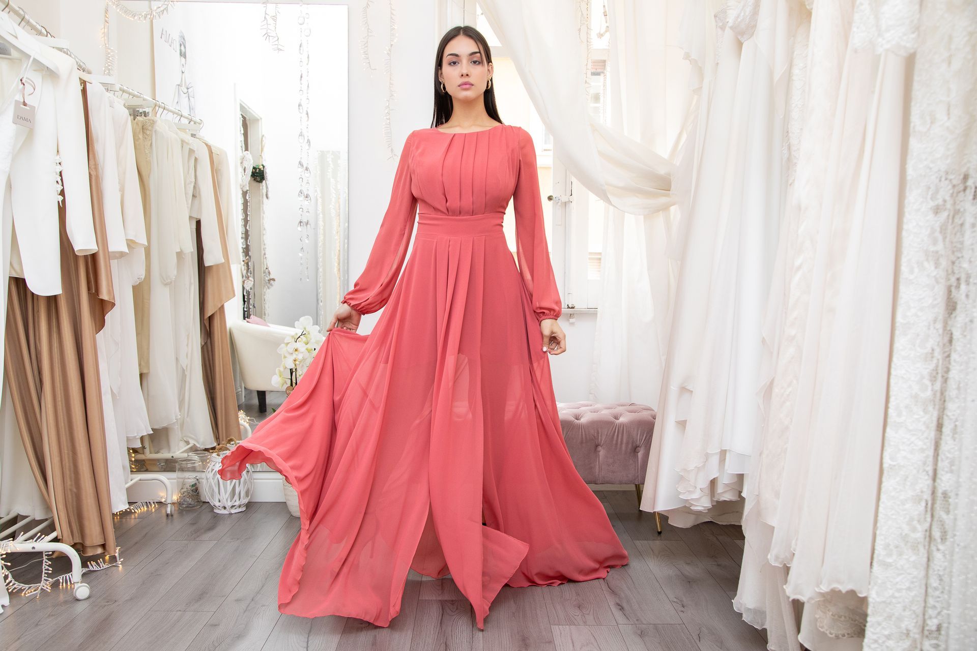 Una donna indossa un lungo abito rosa in un negozio di abiti da sposa.
