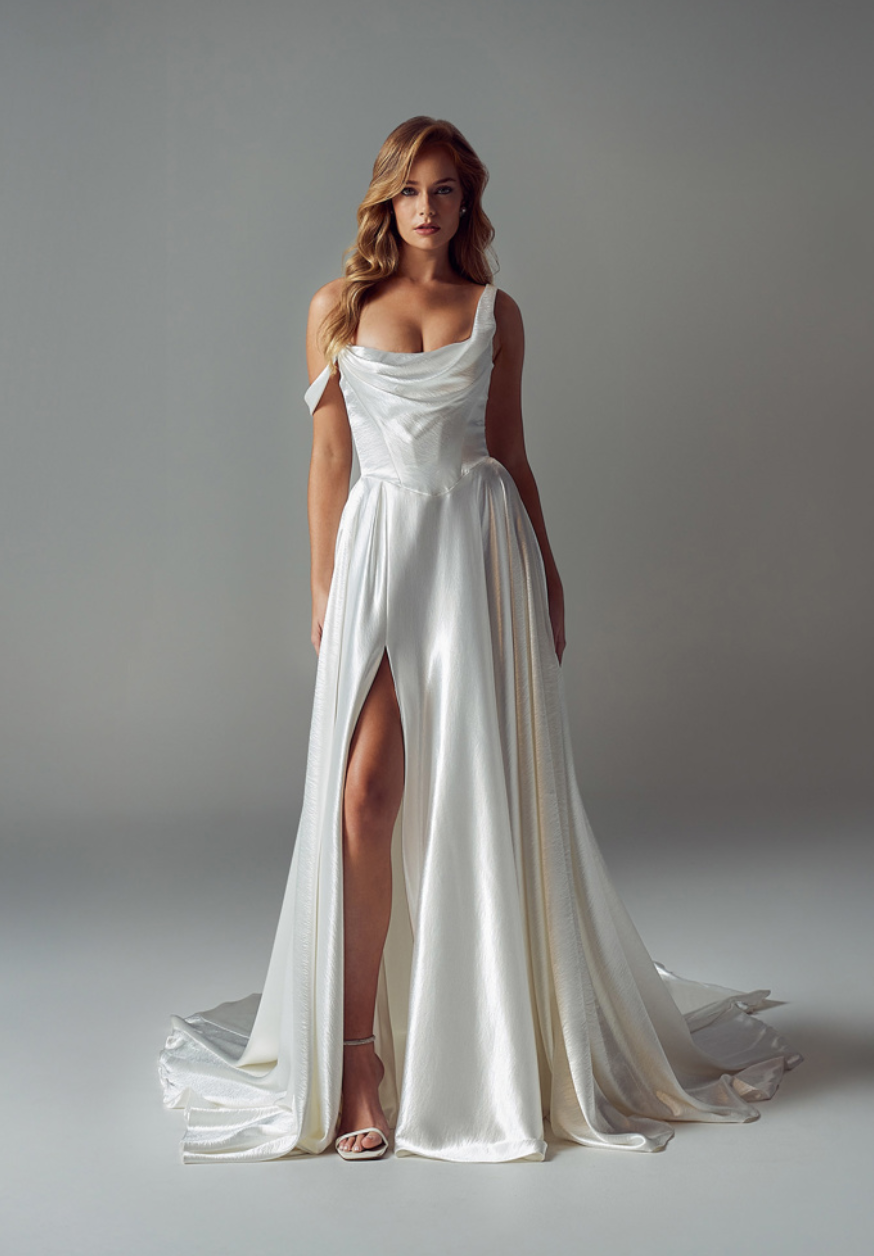 A person wearing a white, floor-length satin gown with a draped cowl neckline, a side shoulder strap, and a high leg slit.