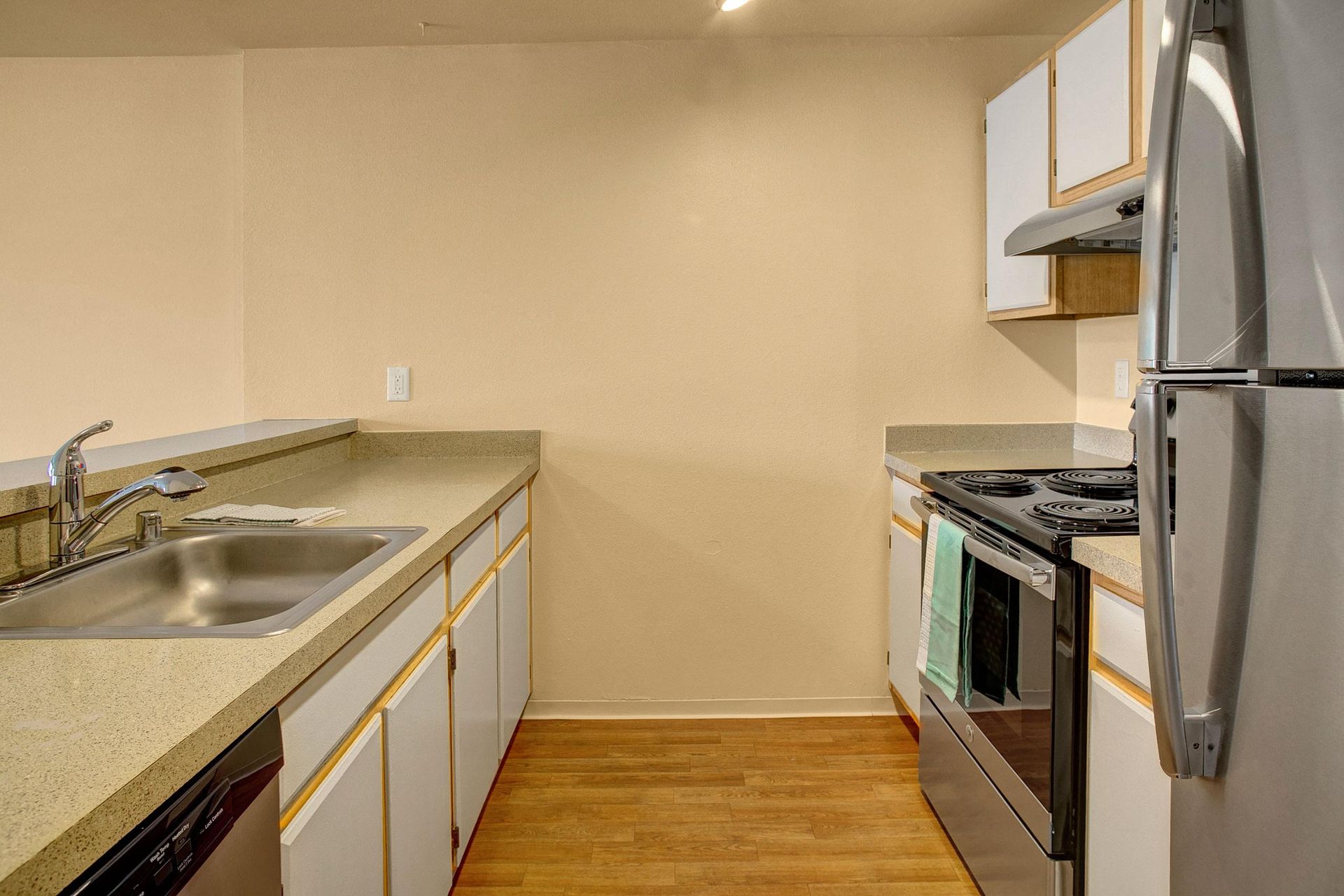 Kitchen with light cabinets, beige countertops, stainless steel appliances, and wood floors.